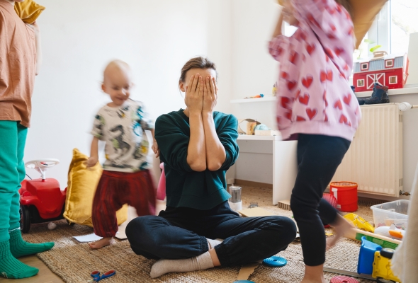 opvoedstress, mama zit uitgeput op de vloer, kinderen lopen rond haar