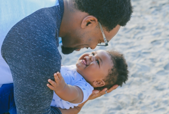 Papa en baby knuffelen op het strand
