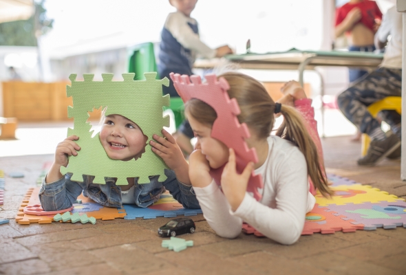 Kinderen spelen op de grond met kleurrijke puzzelmatten