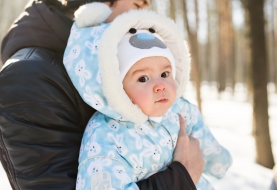 Baby ingeduffeld in winterjas in sneeuwlandschap