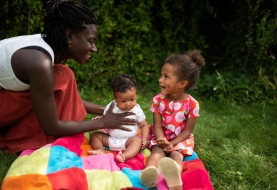 Mama tilt speelt met baby en peuter buiten in de tuin, buiten spelen, dekentje