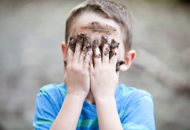 Jongen met modder aan handen bedekt zijn gezicht