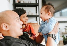 Papa zit met peuter en baby in de zetel en genieten van een gezellig babbelmomentje