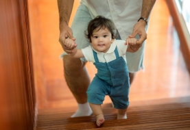 baby loopt aan hand van papa
