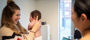 Een verpleegkundige houdt een baby vast op een consultatie