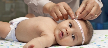 baby ligt op matje terwijl vrijwilliger de hoofdomtrek meet in consultatiebureau