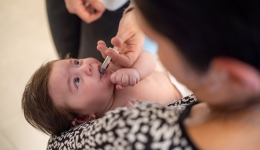 Een baby krijgt een oraal toegediend vaccin in het consultatiebureau