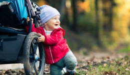 Peuter houdt zich in het bos staande tegen een kinderwagen