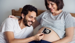 papa houdt echografie boven zwangere buik van mama