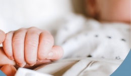 Baby houdt hand vast van ouder