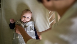 Mama legt baby te slapen in babybed, slaapritueel in veilige slaapomgeving