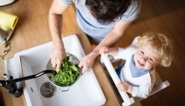 Papa kookt samen met kleuter, groenten wassen in de keuken